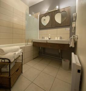 a bathroom with a sink and a tub and a mirror at Logis Hôtel Médiéval, Montélimar Nord in Rochemaure