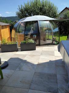 eine Terrasse mit zwei Pflanzen und einem Sonnenschirm in der Unterkunft Chambres d'hôtes Au Doubs Murmure in Les Fins