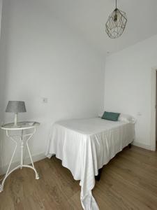 a white bedroom with a bed and a table at HOSTAL LA CRUZ 1872 in Chipiona