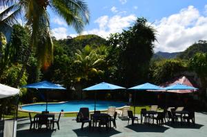 un grupo de mesas y sillas con sombrillas junto a una piscina en Chanchamayo Inn Hotel, en La Merced