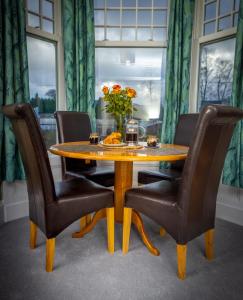 a dining room table with chairs and a vase of flowers at Spacious 1st Floor Apartment in Keswick