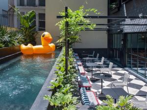 The Editory Boulevard Aliados Hotel - Preferred Hotels في بورتو: مسبح مع بطه مطاطيه كبيره في الماء