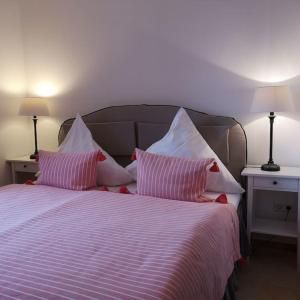 a bed with pink and white striped sheets and pillows at Ferienwohnung Gutshof in Seenähe in Dießen am Ammersee