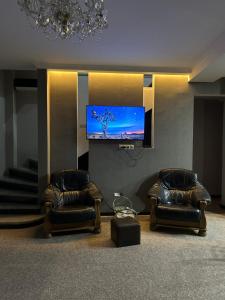 two leather chairs in a living room with a tv at New House in Old Tbilisi in Tbilisi City