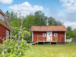 uma pequena casa vermelha com um deque num quintal em Holiday home Edsbruk em Edsbruk