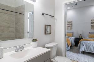 a bathroom with a sink and a toilet and a bedroom at Luxury NOLA House w 6 Bedrooms in New Orleans