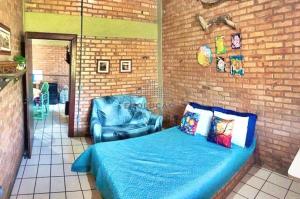 1 dormitorio con 1 cama azul y 1 silla en Chalé Dunas do Beco, en Florianópolis
