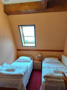 two beds in a small room with a window at Motel Delfin ** in Trojanów