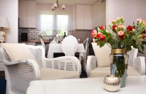 jadalnia z białymi krzesłami i wazonem kwiatów na stole w obiekcie Dom Oleńka- Kaszuby, weekend, wakacje, sauna, jacuzzi, jezioro w mieście Garcz