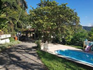 un patio trasero con piscina y una casa en Linda casa no Rio de Janeiro (Itanhangá), en Río de Janeiro