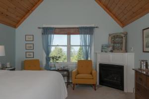 a bedroom with a bed and two chairs and a fireplace at The Bradley Inn in New Harbor