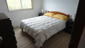 una camera da letto con un letto con un piumone bianco e una finestra di Runa, Marcos de los Reyes villa serrana a Minas