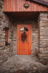 an orange door on a stone building with a wreath on it at Farma František in Stachy