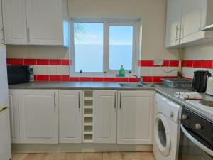 Una cocina con gabinetes blancos y un fregadero y una ventana. en Bright, Comfortable Home, Convenient for City Centre, en Liverpool
