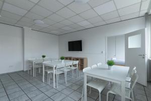 a room with white tables and chairs and a tv at T&K Apartments - 3 - 5 Group Room Apartments- 15min to Fair DUS in Neuss