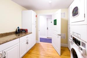a kitchen with white cabinets and a washer and dryer at West Broadway Quarters by Thatch in Boston