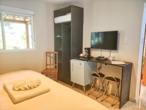 a bedroom with a bed and a desk with a television at Pousada Villa Magna - Suite in Diamantina