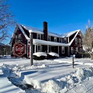 ein Haus ist mit Schnee bedeckt mit schneebedecktem Hof in der Unterkunft The Griff Inn in Waitsfield