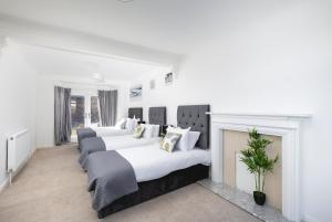 a bedroom with three beds and a fireplace at Skyvillion - London Enfield 4 Bedroom Lush House Free Parking Garden in Enfield Lock