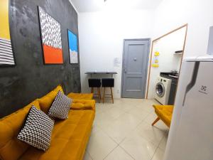 sala de estar con sofá amarillo y cocina en Loft na Praia de Copacabana, maquina de lavar, en Río de Janeiro