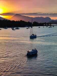 deux bateaux dans une grande étendue d'eau au coucher du soleil dans l'établissement The Manessi City Boutique Hotel, à Poros