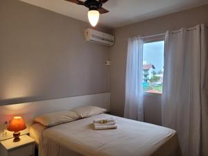 1 dormitorio con 1 cama, ventana y ventilador en Imigrantes Apart Hotel, en Florianópolis