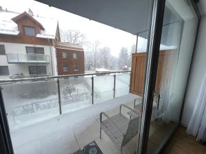 uma varanda com vista para um pátio coberto de neve em Stone Hill SPA by Clima Apartment em Szklarska Poręba