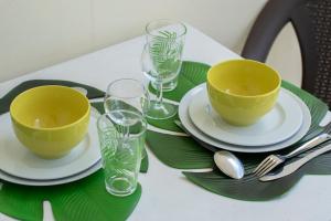 un tavolo con piatti e bicchieri verdi su un tavolo di NOUVEAUTÉ CLÉ EN MAIN - L'EDEN - STUDIO HOTEL CARAYOU: BAR, PISCINE, PLAGES a Les Trois-Îlets