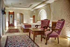 Cappadocia Sweet Cave Hotel في نوشهر: غرفة نوم بسرير وطاولة وكراسي