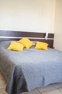 un letto con due cuscini gialli sopra di NOUVEAUTÉ CLÉ EN MAIN - L'EDEN - STUDIO HOTEL CARAYOU: BAR, PISCINE, PLAGES a Les Trois-Îlets