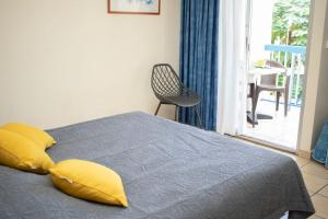 una camera da letto con un letto con cuscini gialli e una sedia di NOUVEAUTÉ CLÉ EN MAIN - L'EDEN - STUDIO HOTEL CARAYOU: BAR, PISCINE, PLAGES a Les Trois-Îlets