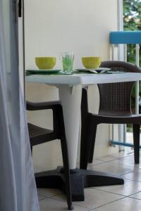 un tavolo bianco con due ciotole e una sedia di NOUVEAUTÉ CLÉ EN MAIN - L'EDEN - STUDIO HOTEL CARAYOU: BAR, PISCINE, PLAGES a Les Trois-Îlets