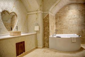 La salle de bains est pourvue d'une baignoire, d'un lavabo et d'un miroir. dans l'établissement Cappadocia Sweet Cave Hotel, à Nevşehir