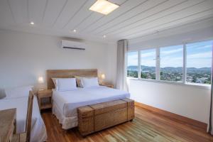 a white bedroom with a bed and large windows at O HOTEL in Búzios