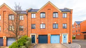 an orange brick building with blue garage doors at Wharf View Townhouse Chester in Chester