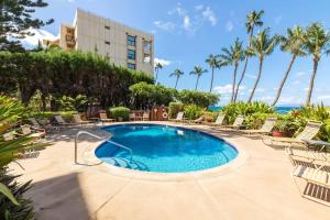 a swimming pool with chairs and the ocean in the background at Kealia Resort 309 in Kihei