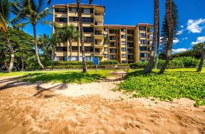 a building with palm trees in front of a beach at Kealia Resort 309 in Kihei