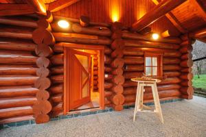 Cabaña de madera con puerta y taburete delante en Mia Bella luxury chalet in Slovenske Konjice, en Slovenske Konjice