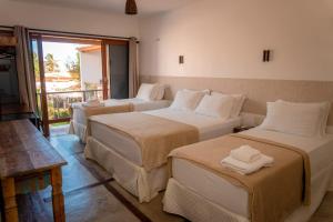 three beds in a room with a balcony at Pousada Morada do Sol in Camocim