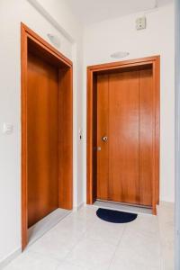pasillo con 2 puertas de madera y suelo de baldosa en Alexandros Apartments, en Mesolongi