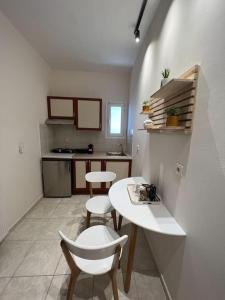 una pequeña cocina con mesa blanca y sillas en Alexandros Apartments, en Mesolongi