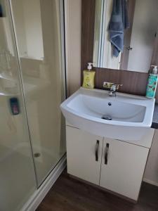 ein Badezimmer mit einem weißen Waschbecken und einer Dusche in der Unterkunft Heysham seaview in Heysham