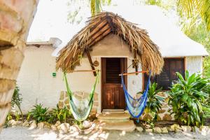 a small house with a thatch roof and a door at Zomay Beachfront Holbox in Holbox Island