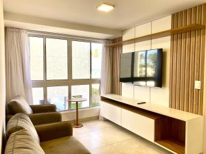 uma sala de estar com um sofá, uma televisão e uma janela em PUERTO VENTURA Flat - Cabo Branco by PenareiaTurBr em João Pessoa