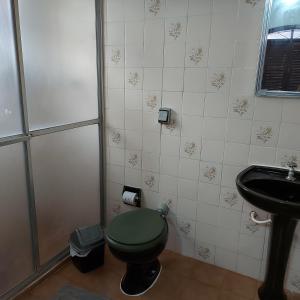 La salle de bains est pourvue de toilettes vertes et d'un lavabo. dans l'établissement Casa no Guaraú - Peruíbe, à Peruíbe