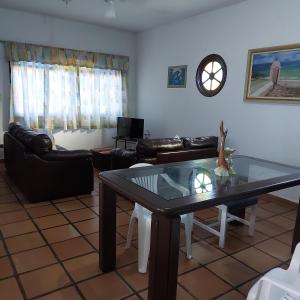 a living room with a glass table and leather furniture at Casa no Guaraú - Peruíbe in Peruíbe