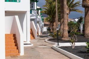 a sidewalk with palm trees and a white building at Casa Su, precioso apartamento en complejo con piscina in Puerto del Carmen