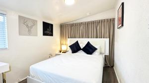 1 dormitorio con 1 cama blanca grande con almohadas azules en Spacious, Private, Modern 4 Bedroom House Plus Game Room, en Glendale