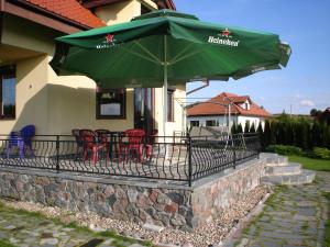 einen Balkon mit Stühlen und einem grünen Sonnenschirm in der Unterkunft Wypoczynek na Mazurach u Kamili in Konopki Wielkie