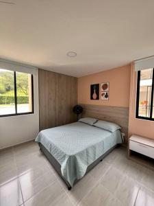 a bedroom with a large bed and two windows at Elegante apartamento in Cartago